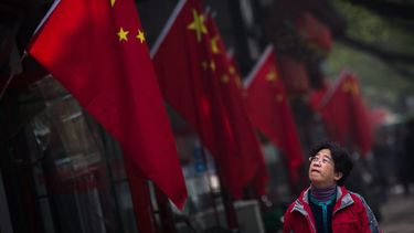 Una mujer pasa junto a una bandera&nbsp;china&nbsp;colgada en el barrio de Hutong durante la tercera jornada del el XIX Congreso del Partido Comunista de&nbsp;China&nbsp;(PCCh) en Pekín (China)el pasado 20 de octubre de 2017.&nbsp;