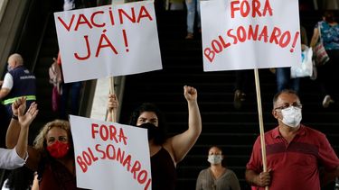 Manifestantes muestran carteles con las frases ¡Vacuna ya! y ¡Fuera Bolsonaro (en portugués) durante una protesta contra la gestión del presidente del país, Jair Bolsonaro, durante la pandemia del coronavirus, en una estación de autobús en Brasilia, Brasil, el 23 de diciembre de 2020