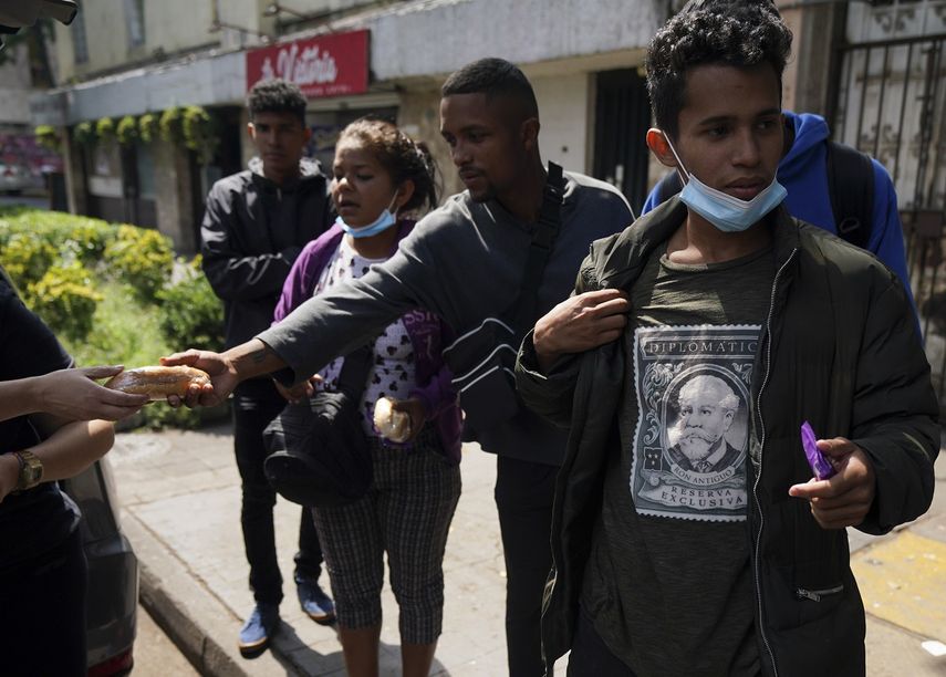 Voluntarios reparten comida a migrantes venezolanos que buscan ayuda en el exterior de la Comisión Mexicana de Ayuda a Refugiados, en la Ciudad de México, el 20 de octubre de 2022.