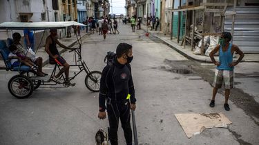 Con una máscara facial en medio de la pandemia del nuevo coronavirus, el buzo Yuniel González camina a casa con su pesca del día en La Habana, Cuba, el martes 27 de octubre de 2020.