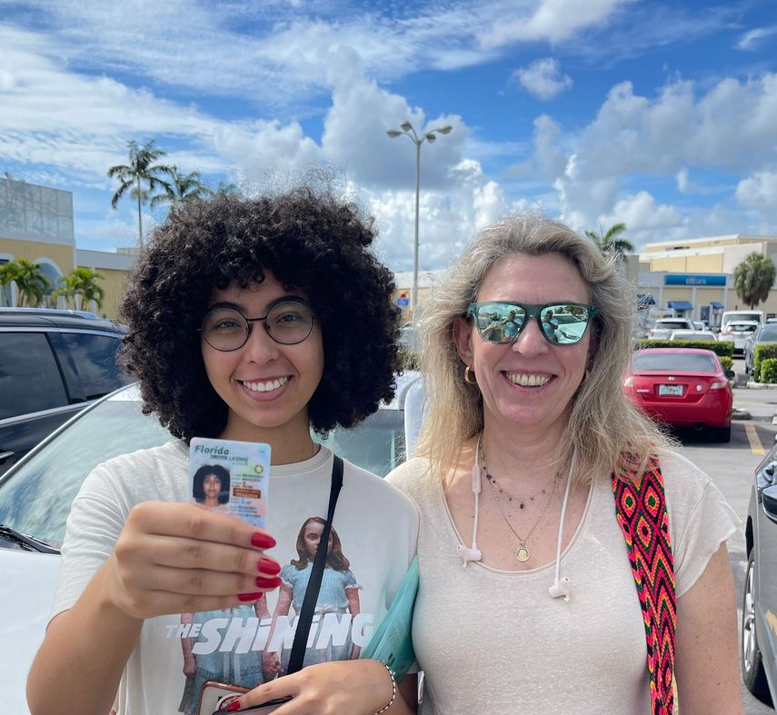 Lucía, junto a su madre, muestra el carné de conducir que acaba de obtener en una oficina Miami-Dade.