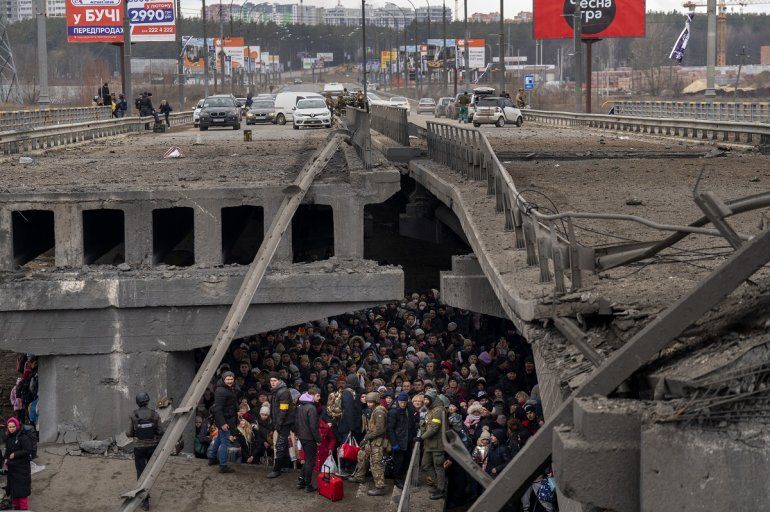 Ucranianos se agolpan bajo un puente destruido mientras intentan huir a través del río Irpin en las afueras de Kiev, Ucrania, el sábado 5 de marzo de 2022. 