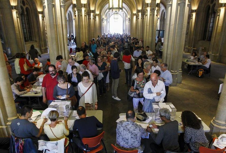 Colas de ciudadanos esperan su turno para votar en un colegio electoral de Barcelon. (EFE)