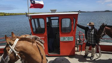 Un hombre mapuche cruza con sus caballos sobre el río Imperial en un ferry, un día antes de un eclipse solar total en Carahue, La Araucanía, Chile el domingo 13 de diciembre de 2020. El eclipse total será visible desde Chile y la región norte de la Patagonia de Argentina y como eclipse solar parcial en Bolivia, Brasil, Ecuador, Paraguay, Perú y Uruguay.&nbsp;