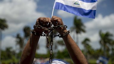 Un hombre con cadenas en las manos y una bandera de Nicaragua,