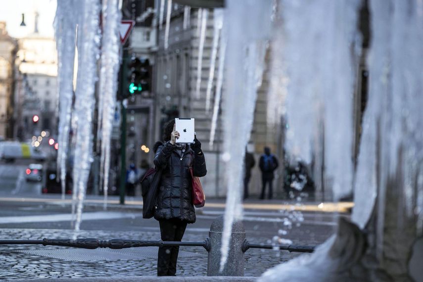 Una mujer fotografía la Fuente de Tritón helada en la plaza de Barberini en Roma (Italia)&nbsp;