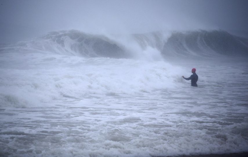 Matt Prue, de Stonington, Connecticut, camina en el Océano Atlántico para surfear las olas de la tormenta tropical Henri mientras el sistema se aproximaba, en Rhode Island, el domingo 22 de agosto de 2021.&nbsp;