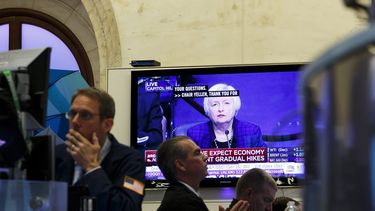 Una pantalla muestra una imagen de la presidenta de la Reserva Federal estadounidense,&nbsp;Janet&nbsp;Yellen, mientras varios agentes de Bolsa realizan su trabajo en el parqué de Nueva York
