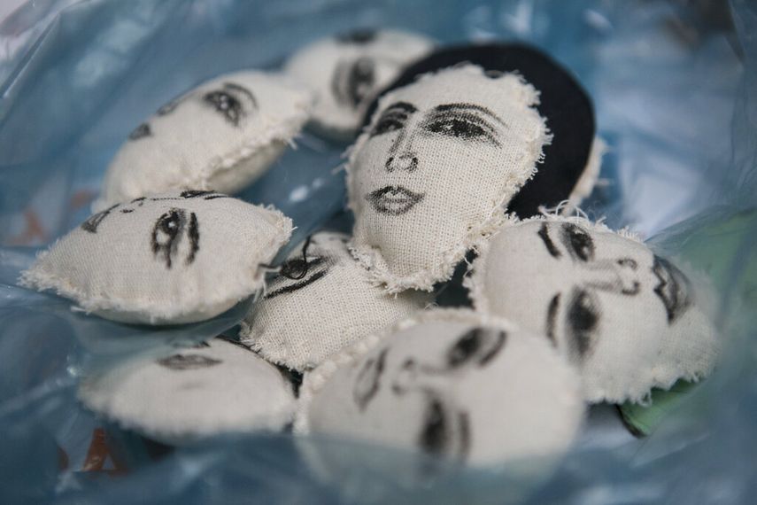 Los rostros de mujeres pintados a mano decoran unas almohadillas que Erika Martínez convertirá en llaveros, que vende para lograr algo de dinero mientras vive con su hija en las ocupadas oficinas de la Comisión Nacional de Derechos Humanos, que se han convertido en un refugio para víctimas de la violencia de género como ellas, en la Ciudad de México, el 17 de noviembre de 2020.