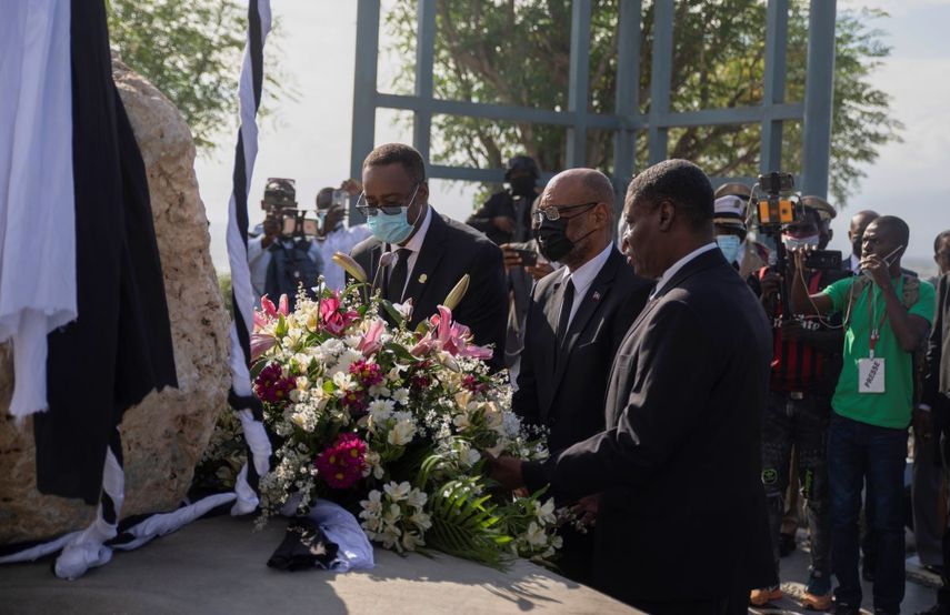 El primer ministro haitiano Ariel Henry (centro) coloca un ramo de flores en un monumento en memoria de las víctimas del sismo de 2010, en Puerto Príncipe, Haití, el miércoles 12 de enero de 2022.