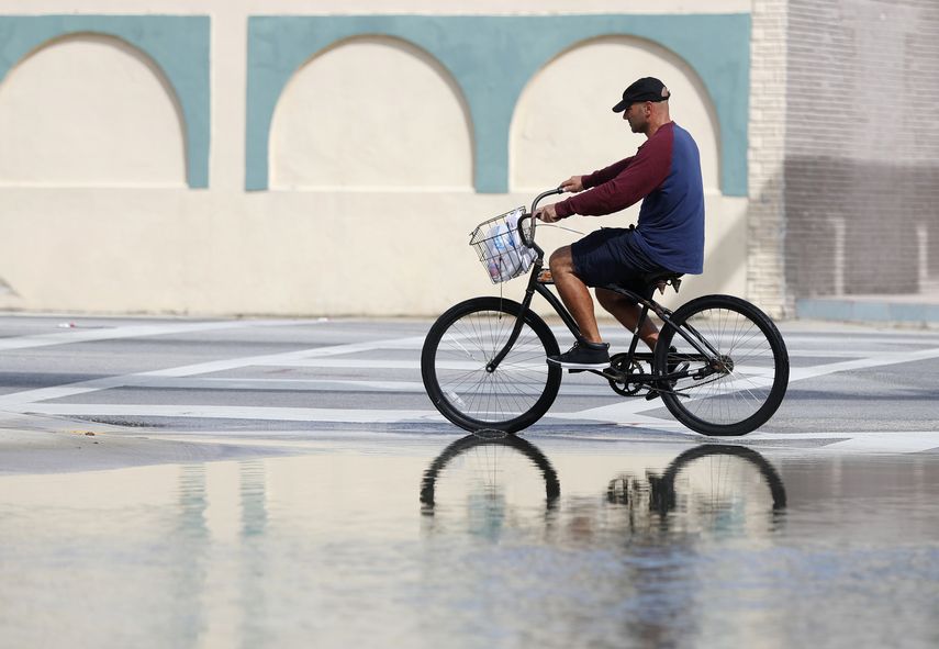 Fotografía de archivo del 9 de octubre de 2018 de un ciclista pasando frente a un área inundada en Miami.