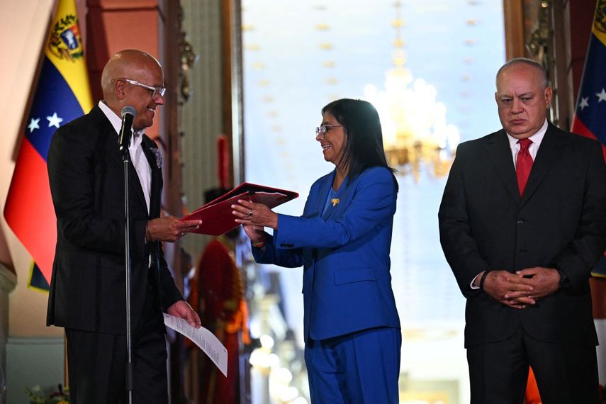 La gobernante interina de Venezuela, Delcy Rodríguez, recibe la ley de amnistía de manos de su hermano y presidente de la Asamblea Nacional, Jorge Rodríguez, mientras el ministro del Interior, Justicia y Paz, Diosdado Cabello, expresa malestar en su rostro durante la entrega de la ley, en el Palacio de Miraflores en Caracas el 19 de febrero de 2026.