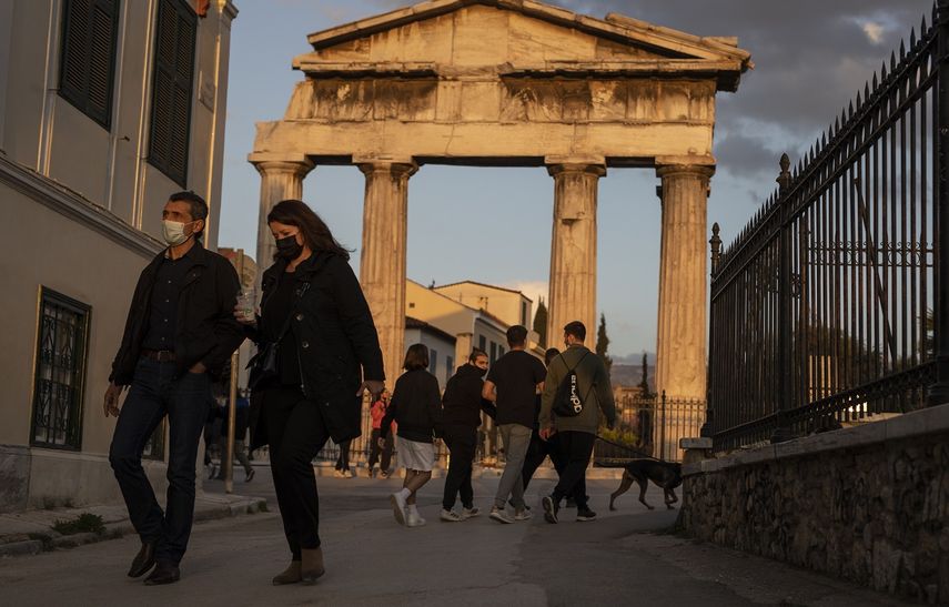 Personas con mascarillas caminan frente a la puerta del antiguo ágora romano, en Plaka, un distrito de Atenas, el martes 6 de abril de 2021.&nbsp;