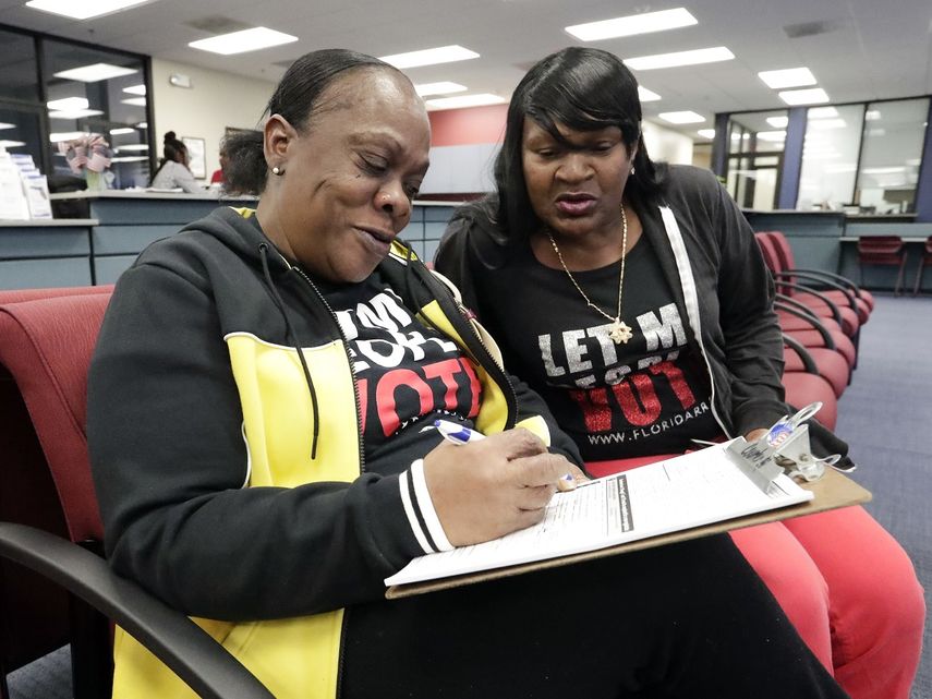 Fotografía de archivo del 8 de enero de 2019 de la exdelincuente Yolanda Wilcox (izquierda), mientras llena una forma de registro de votantes, acompañada de su amiga Gale Buswell, en una oficina electoral en Orlando, Florida.