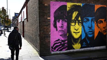 Los peatones pasan frente a un mural que representa a miembros de la banda de rock británica The Beatles: Ringo Starr, John Lennon, Paul McCartney y George Harrison en el costado de un edificio en Liverpool, noroeste de Inglaterra, el 13 de octubre de 2020. &nbsp;