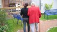 Una mujer y una anciana auxiliada con un bastón caminan sobre una calle.