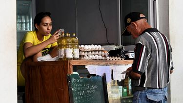 Comprar comida básica es un lujo en la isla. Hombre busca el dinero frente a una tienda de alimentos.