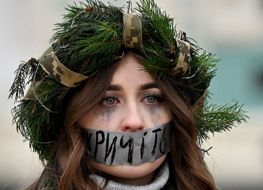 Una manifestante lleva una corona navideña y se tapa la boca con un lema que dice Grita durante una manifestación para pedir el intercambio de prisioneros de guerra ucranianos de la Brigada Azov y otras unidades por prisioneros rusos en la plaza de Santa Sofía en Kiev el 29 de diciembre de 2024, en medio de la invasión rusa en Ucrania.&nbsp;