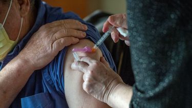 Empleada de la salud vacuna a una persona de la tercera edad.