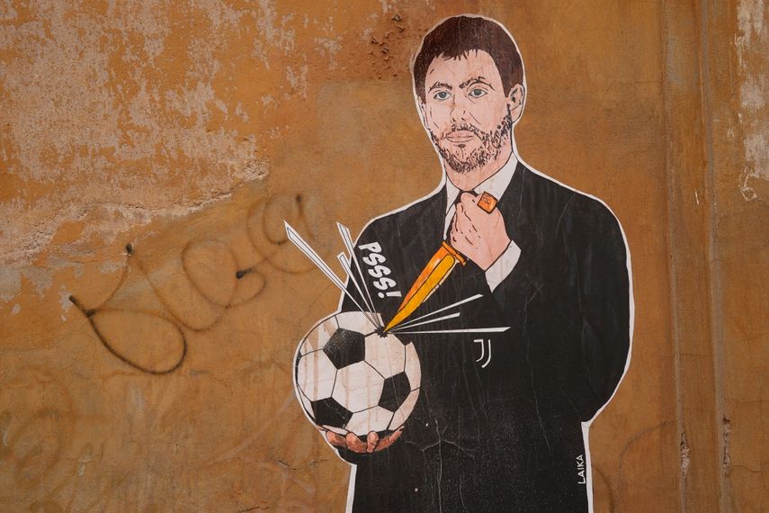 Un mural con una imagen del presidente de Juventus abriéndole un agujero a una pelota de fútbol, en Roma, el jueves 22 de abril de 2021