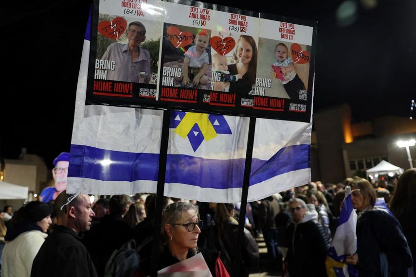 La gente lleva una pancarta con las fotografías de Oded Lifshitz y miembros de la familia Bibas, horas después de que el grupo palestino Hamás entregara los cuerpos de quienes dijo que eran los de los cuatro rehenes, el 20 de febrero de 2025.&nbsp;