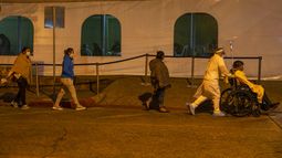 Mujeres que llevan m&aacute;scaras protectoras siguen a un pariente en silla de ruedas que ingresar&aacute; a la unidad de coronavirus en el hospital de la Seguridad Social en la Ciudad de Guatemala