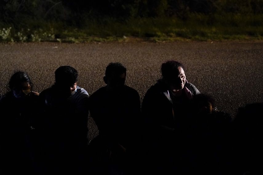 En esta imagen de archivo, tomada el 17 de mayo de 2021, un grupo de migrantes, en su mayoría de Honduras y Nicaragua, esperan en una carretera tras entregarse a las autoridades luego de cruzar la frontera entre México y Estados Unidos, en La Joya, Texas.&nbsp;