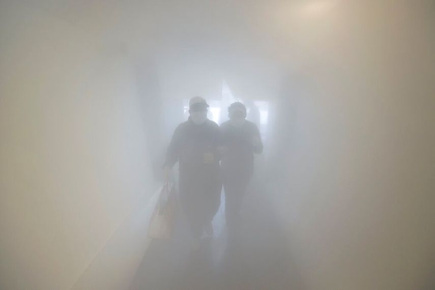 Una pareja con mascarilla pasa por una sala de descontaminaci&oacute;n como medida de precauci&oacute;n contra la propagaci&oacute;n del coronavirus antes de entrar a una tienda, en Caracas, Venezuela.