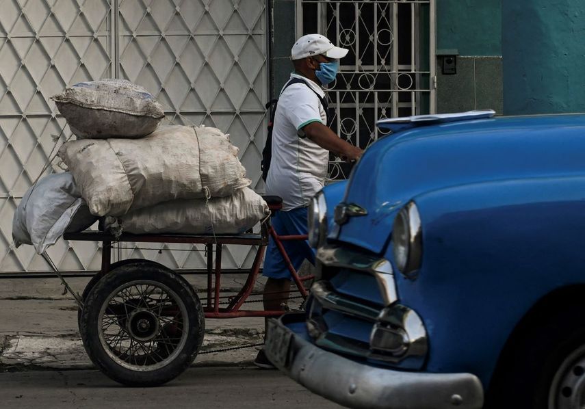 Un hombre usa mascarilla mientras traslada productos en su bicicleta en una calle de La Habana.