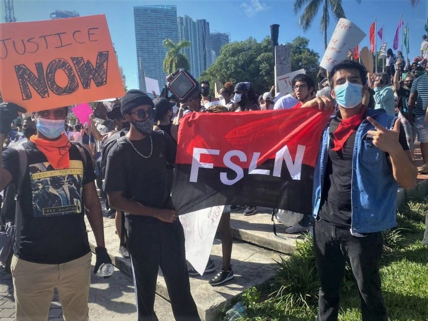 Activistas del Frente Sandinista participando en las protestas en Miami, con la bandera del partido de la dictadura de Daniel Ortega.