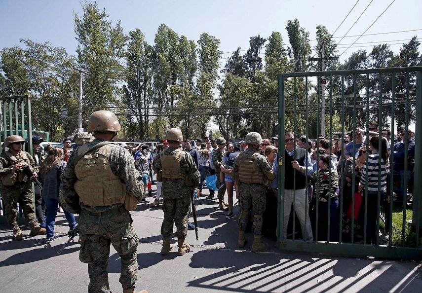 La polic&iacute;a militar vigila un supermercado mientras la gente hace fila para esperar a que abra, en Santiago, Chile, el lunes 21 de octubre de 2019.&nbsp;