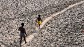 Un hombre y un niño caminan a través del lecho casi seco del río Yamuna luego de una ola de calor, el lunes 2 de mayo de 2022, en Nueva Delhi. 