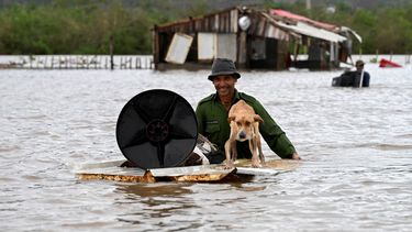 Un agricultor rescata a su perro y algunas pertenencias de su casa inundada después de que el huracán Melissa pasó por la localidad de San Miguel de Parada en la provincia de Santiago de Cuba el 29 de octubre de 2025.