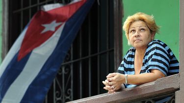 Una mujer mira desde un balcón en La Habana.