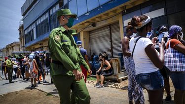 Un soldado vigila afuera de una tienda estatal de comida donde las personas esperan en línea para entrar en La Habana, Cuba, el martes 19 de mayo de 2020.