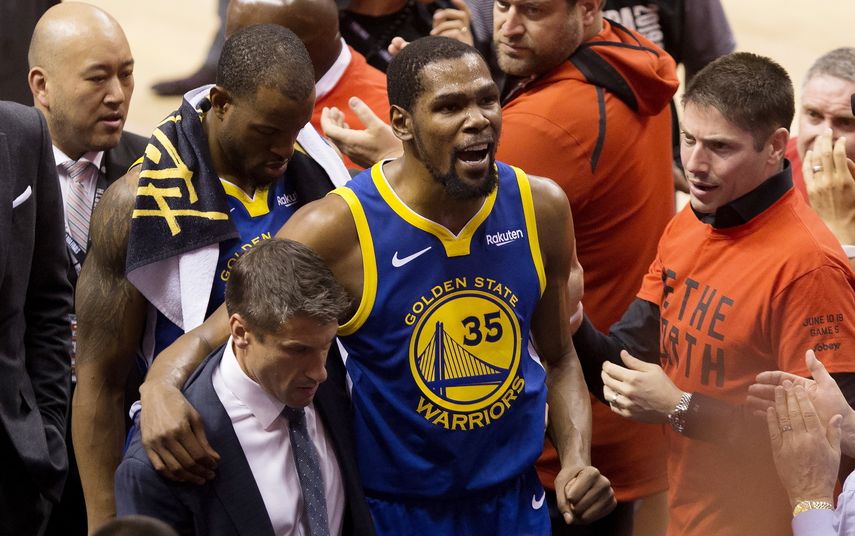 Kevin Durant, alero de los Warriors de Golden State, es ayudado a salir de la cancha tras lesionarse durante el quinto partido de la Final de la NBA ante los Raptors de Toronto, el lunes 10 de junio de 2019