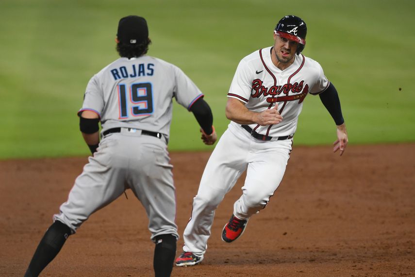 Adam Duvall de los Bravos de Atlanta corre hacia la tercera base mientras el campocorto de los Marlins de Miami Miguel Rojas (19) mira hacia los jardines durante un juego de béisbol el lunes 21 de septiembre de 2020 en Atlanta.&nbsp;
