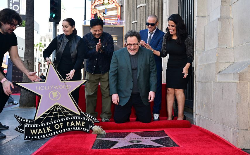El actor estadounidense Robert Downey Jr. coloca el primer chicle en la recién inaugurada estrella del Paseo de la Fama de Hollywood de John Favreau el 13 de febrero de 2023 en Hollywood, California, mientras Favreau y el chef Roy Choi reaccionan.