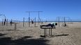 Un hombre hace ejercicios con una distancia prudencial de otro en la Muscle Beach de Santa Monica, California.&nbsp;