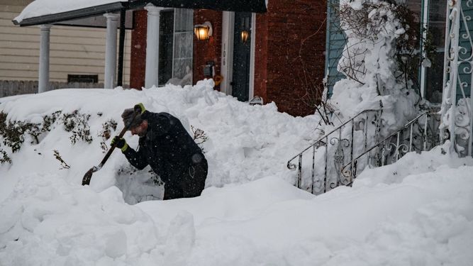 Un hombre limpia la nieve que casi ha sepultado su residencia en Nueva York.