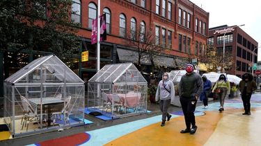 Personas caminan frente a mesas para comensales cubiertas con plástico como protección contra el coronavirus el domingo 18 de octubre de 2020, en Fulton Market, Chicago.&nbsp;