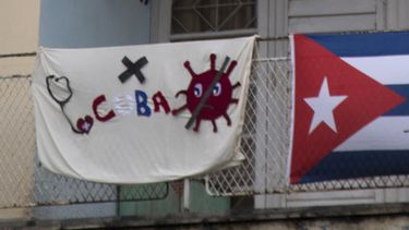 Vista de una tela con la imagen del nuevo coronavirus, el cartel de Cuba y un estet&oacute;scopo en un balc&oacute;n de La Habana.