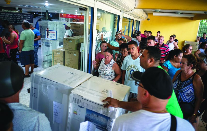 Un trabajador de una tienda transporta mercanc&iacute;as mientras los compradores hacen cola en La Habana, Cuba.&nbsp;