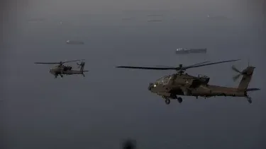 Helicópteros AH-64 Apaches del Ejército de Estados Unidos sobrevuelan el Estrecho de Ormuz durante una operación de patrullaje. Los soldados están proporcionando una presencia visible en apoyo a la libertad de navegación.