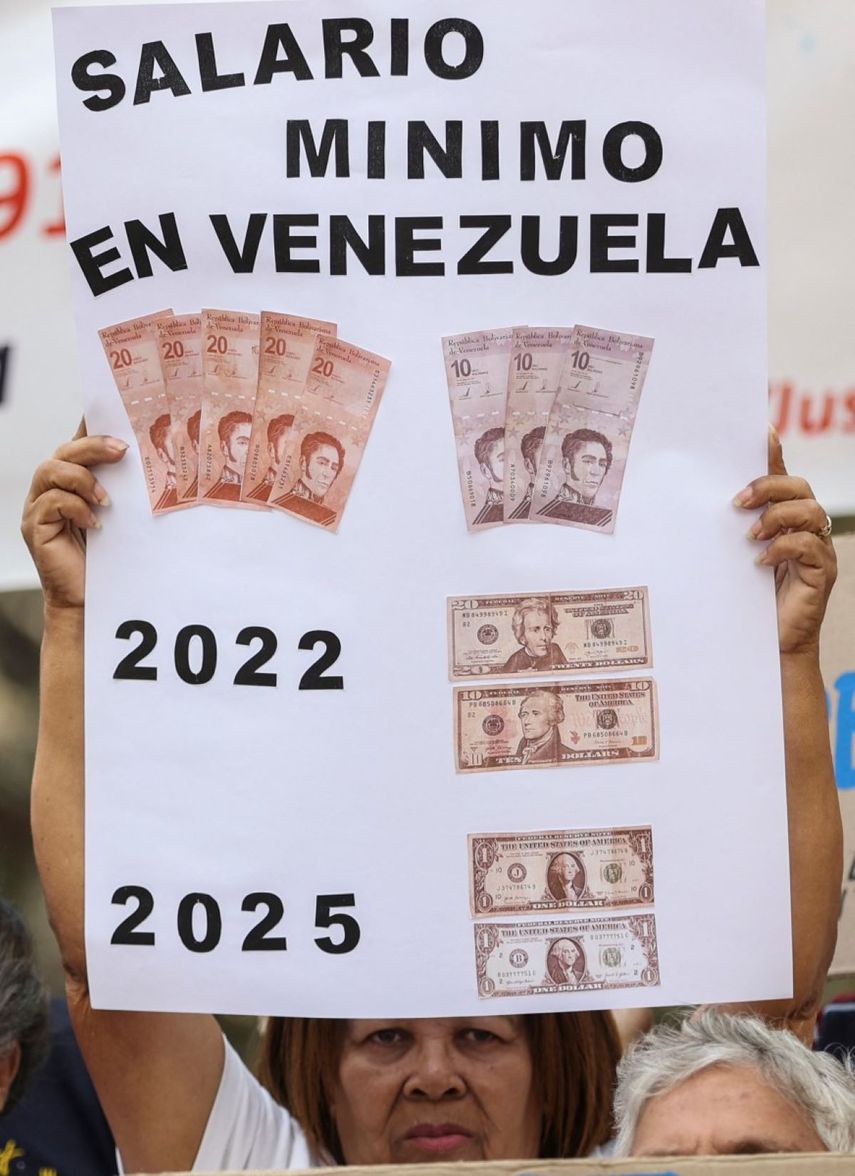 Una mujer sostiene un cartel que muestra el salario mínimo diario aproximado en Venezuela durante una protesta para exigir mejores salarios y pensiones en Caracas el 13 de marzo de 2025. (Foto de Pedro MATTEY / AFP)