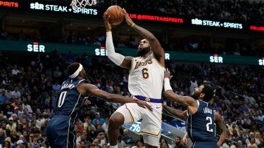 El alero de los Lakers de Los Ángeles LeBron James lanza el balón frente a Justin Holiday y Kyrie Irving de los Mavericks de Dallas en el encuentro del domingo 26 de febrero del 2023.&nbsp;
