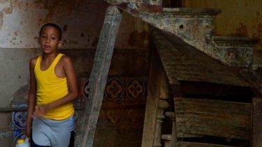 Un niño sale de un edificio en peligro de derrumbe en Centro Habana en busca de agua.&nbsp;
