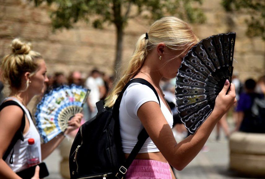 Dos mujeres usan abanico de manos para mitigar el calor abrasador que afecta el país, en Sevilla, España.