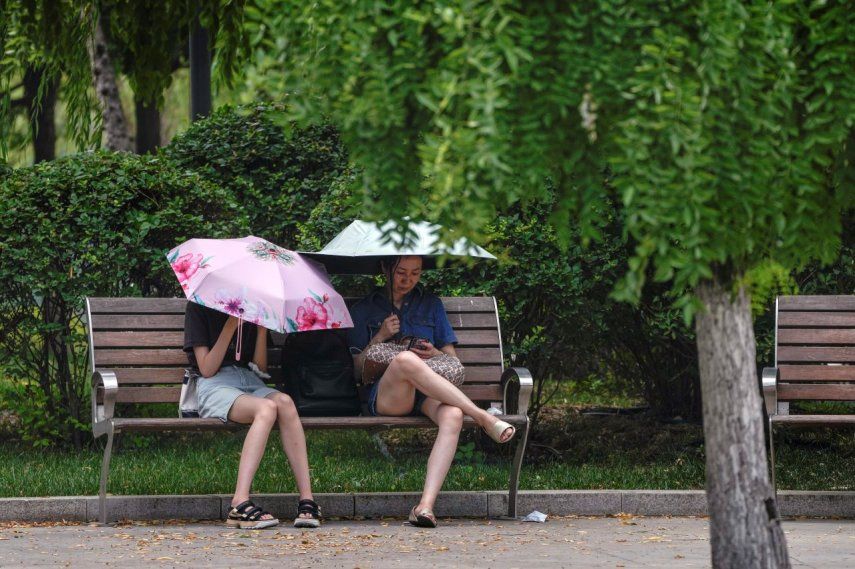 Dos mujeres se cubren del sol durante un día caluroso en Beijing, el lunes 3 de julio de 2023.&nbsp;