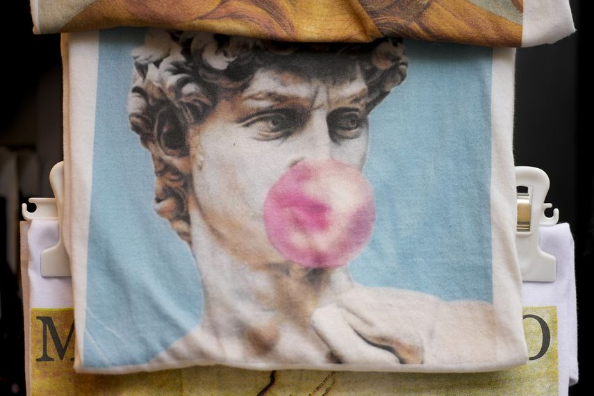 Una bolsa con un estampado de la estatua de David de Miguel Ángel del siglo XVI con una bomba de chicle a la venta, entre otros recuerdos, en una tienda en el centro de Florencia, centro de Italia, el lunes 18 de marzo de 2024.